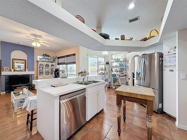 kitchen with a kitchen island with sink, a sink, visible vents, a textured ceiling, and appliances with stainless steel finishes