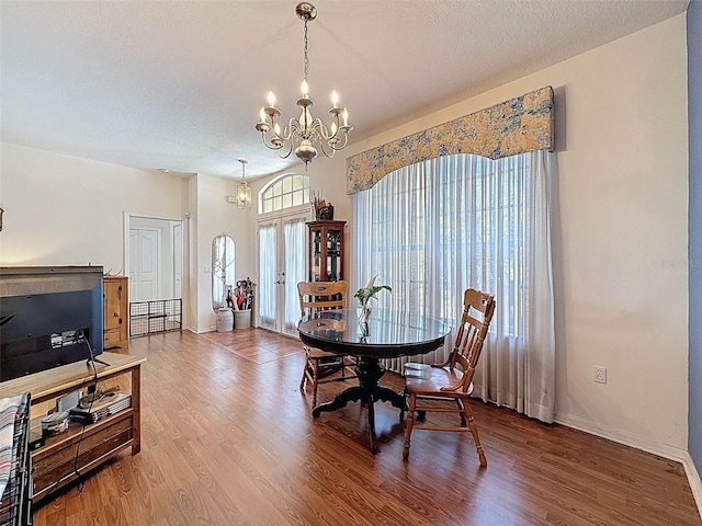 dining area with a chandelier, baseboards, wood finished floors, and a textured ceiling