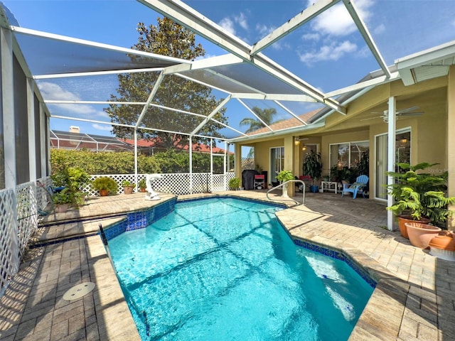 pool with a patio, glass enclosure, and a ceiling fan