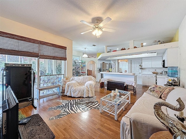 living area with wood finished floors, ceiling fan, and a textured ceiling