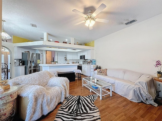 living area with a textured ceiling, visible vents, and arched walkways
