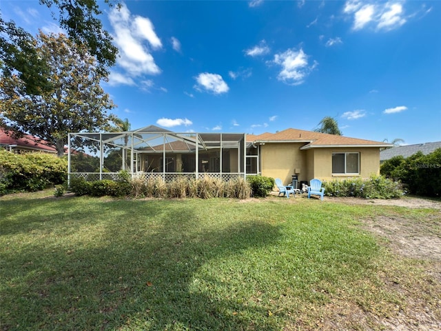 back of house with stucco siding, a yard, and glass enclosure