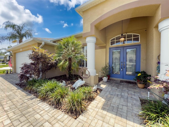 entrance to property with a garage, stucco siding, and french doors