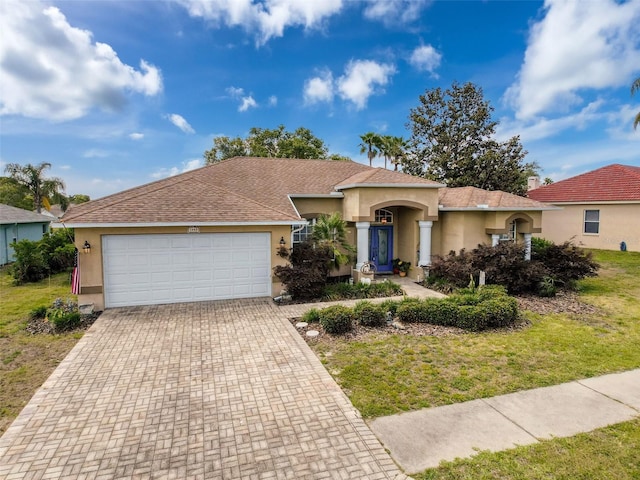 ranch-style house featuring decorative driveway, a front lawn, a garage, and stucco siding