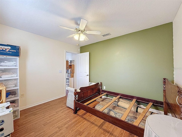 bedroom with wood finished floors, visible vents, ceiling fan, and baseboards