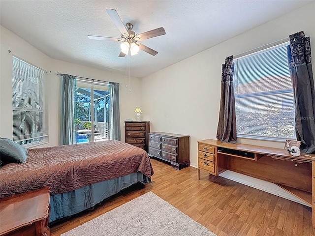 bedroom with a textured ceiling, light wood-style floors, access to exterior, baseboards, and a ceiling fan