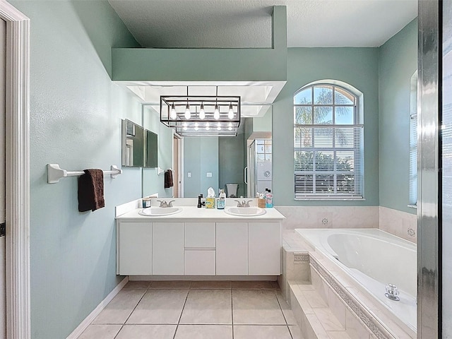 bathroom featuring tile patterned floors, double vanity, a bath, and a sink