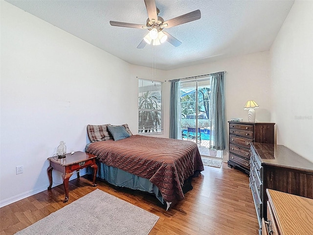 bedroom featuring access to outside, a ceiling fan, baseboards, a textured ceiling, and wood finished floors