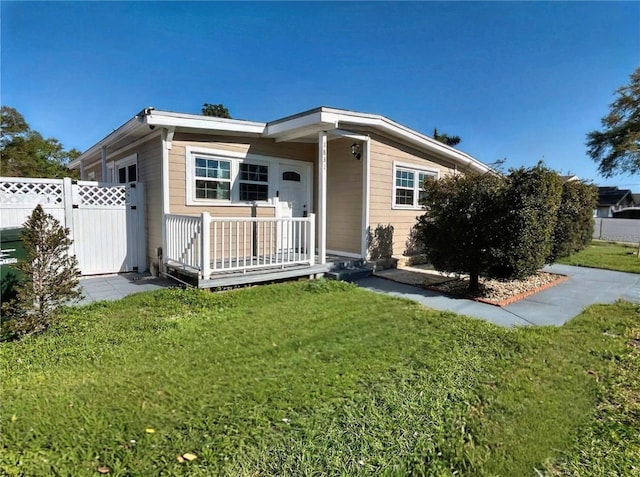 view of front of property featuring a front lawn, a gate, fence, and covered porch