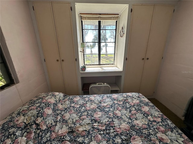 bedroom with a wall mounted air conditioner and two closets