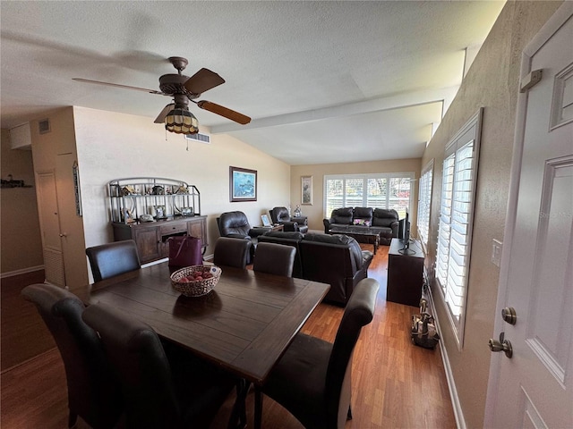 dining space with baseboards, visible vents, lofted ceiling, light wood-style flooring, and a textured ceiling