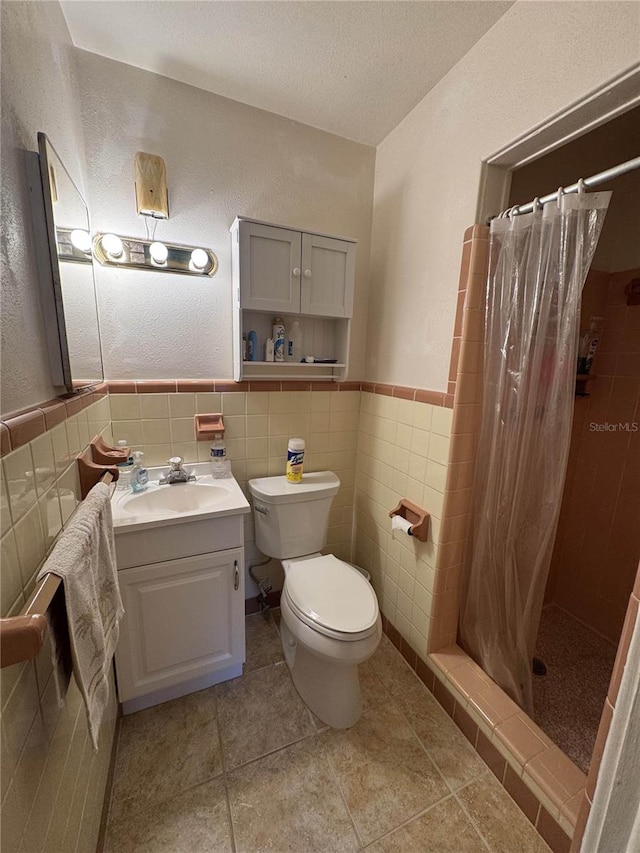 bathroom featuring wainscoting, toilet, vanity, a shower stall, and tile walls