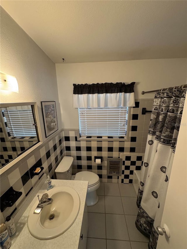 full bath featuring tile walls, toilet, vanity, a textured ceiling, and tile patterned floors