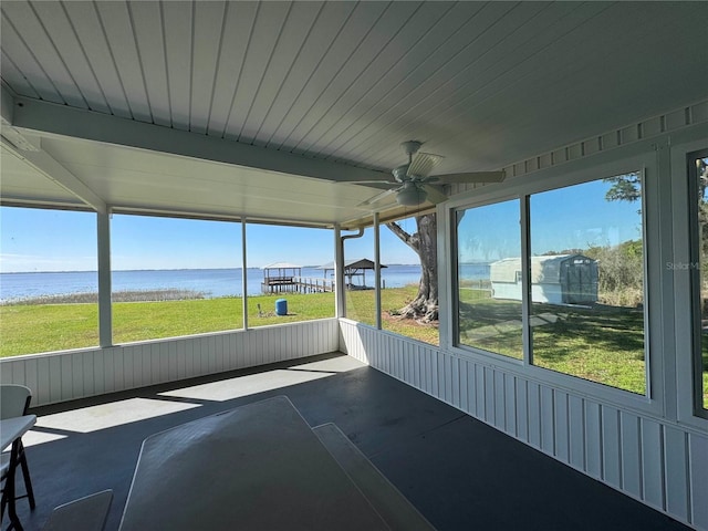 unfurnished sunroom featuring ceiling fan and a water view