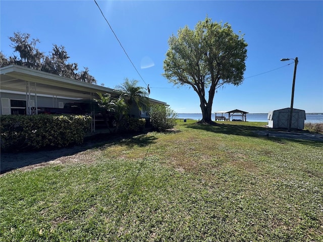 view of yard featuring a storage shed, an outbuilding, and a water view