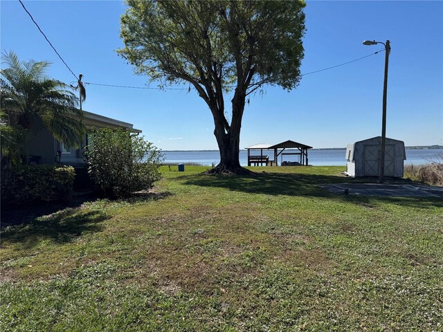 view of yard with an outbuilding, a storage shed, a water view, a gazebo, and a carport