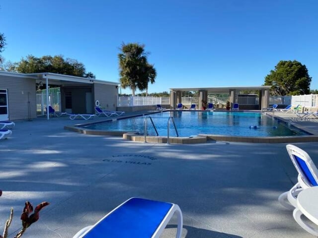 community pool with fence and a patio