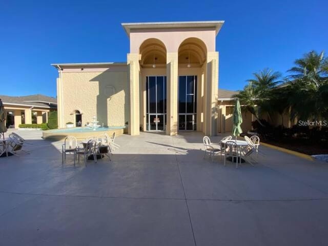 back of property featuring outdoor dining space, a patio, and stucco siding