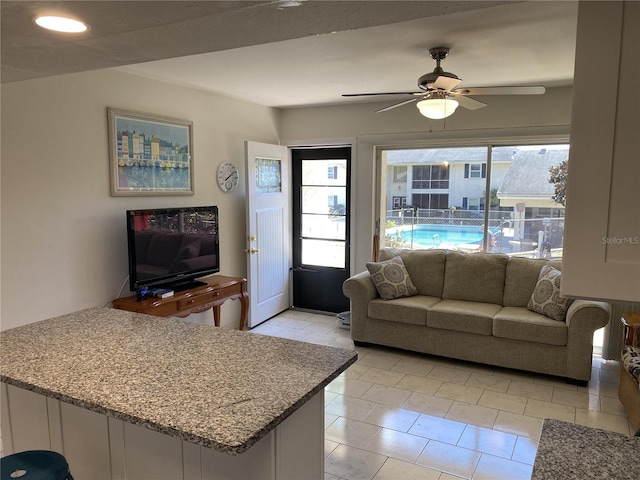 living area featuring ceiling fan, light tile patterned floors, and a healthy amount of sunlight