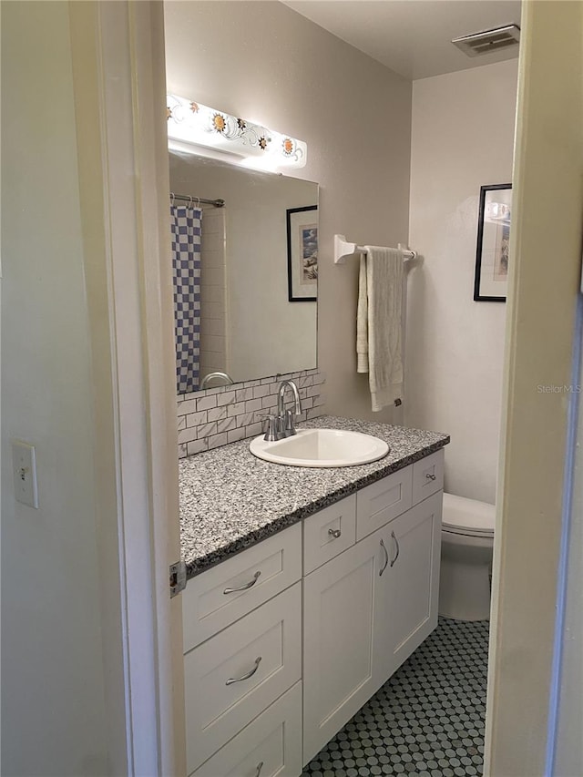 full bath featuring toilet, tasteful backsplash, visible vents, and vanity