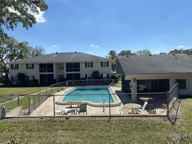 pool with a patio area, fence, and a yard