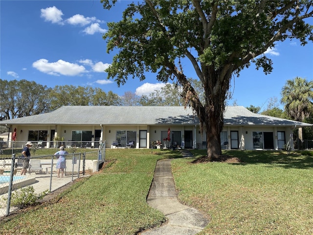 ranch-style house featuring fence, a front lawn, and stucco siding