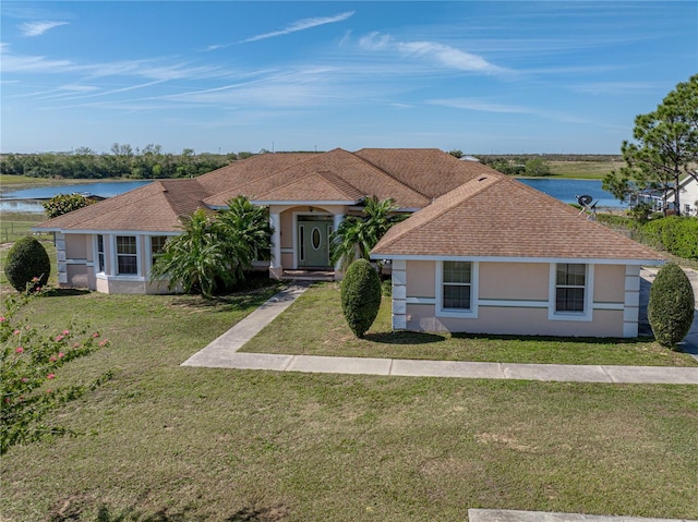 view of front of home featuring a water view, roof with shingles, a front lawn, and stucco siding