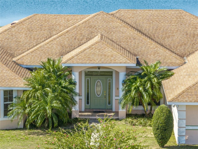 exterior space with a shingled roof and stucco siding