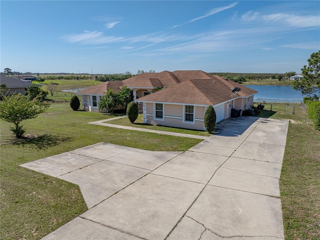 view of front of house featuring a shingled roof, a water view, concrete driveway, stucco siding, and a front lawn