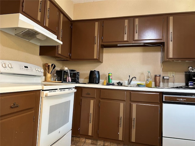 kitchen featuring under cabinet range hood, white appliances, a sink, and light countertops