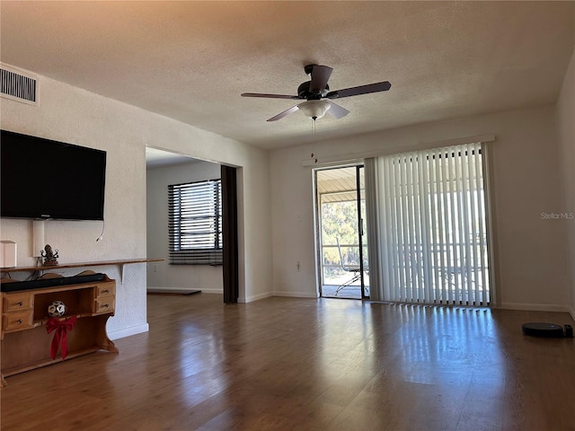 living area featuring wood finished floors, visible vents, a wealth of natural light, and a textured ceiling