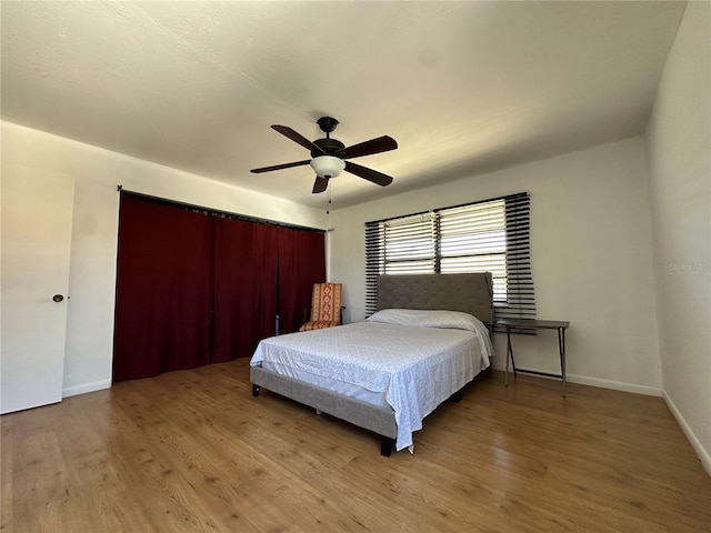 bedroom with a ceiling fan, baseboards, and wood finished floors