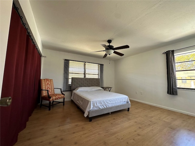 bedroom featuring baseboards, a textured ceiling, and light wood finished floors