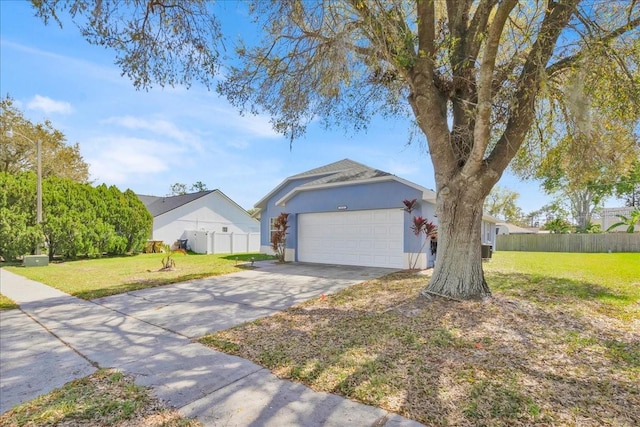 view of front of house featuring concrete driveway, an attached garage, fence, a front lawn, and stucco siding