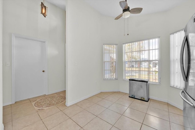 unfurnished room featuring baseboards, ceiling fan, a high ceiling, and light tile patterned floors