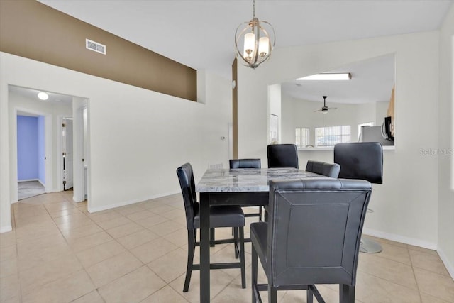 dining space with a notable chandelier, lofted ceiling, visible vents, light tile patterned flooring, and baseboards