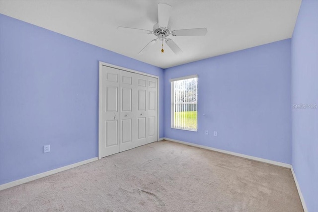 unfurnished bedroom with a closet, carpet flooring, ceiling fan, and baseboards