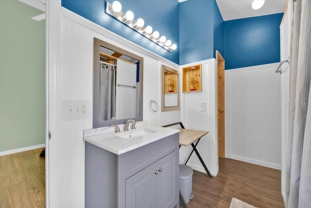 full bath featuring a wainscoted wall, wood finished floors, and vanity