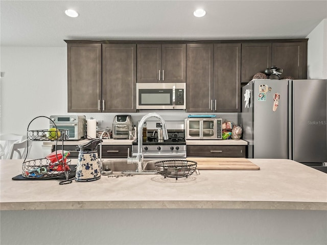 kitchen featuring recessed lighting, appliances with stainless steel finishes, a toaster, dark brown cabinets, and light countertops