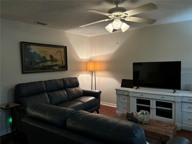 living room featuring baseboards, dark wood finished floors, a textured ceiling, visible vents, and ceiling fan