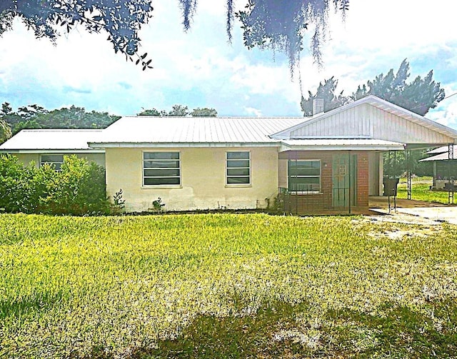 352 E Hwy 630 E, Frostproof, FL 33843 - ranch-style home with a front lawn, stucco siding, a metal roof, and a carport