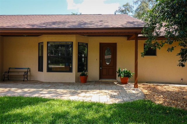 3567 Red Oak Ct, Lake Wales, FL 33898 - doorway to property featuring a shingled roof, stucco siding, and a patio area
