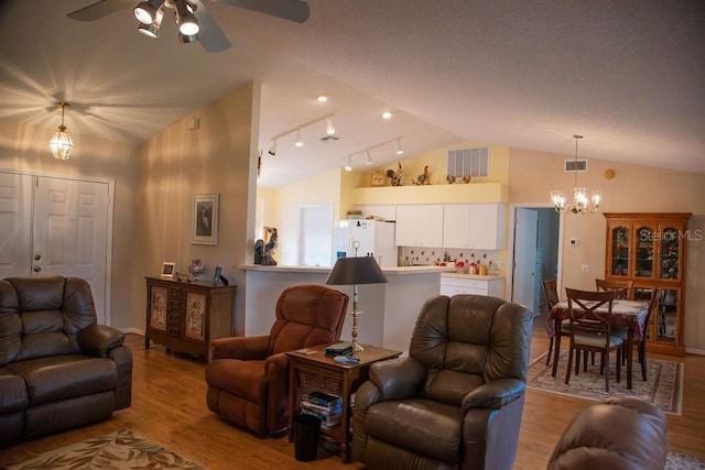 living area featuring visible vents, ceiling fan with notable chandelier, wood finished floors, and lofted ceiling