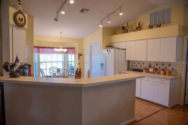 kitchen featuring visible vents, an inviting chandelier, white fridge with ice dispenser, light countertops, and vaulted ceiling