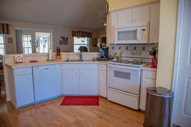 kitchen with a sink, light countertops, white appliances, and a peninsula