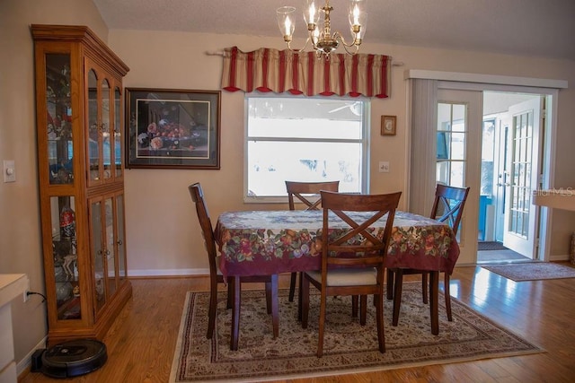 dining space with a notable chandelier, wood finished floors, and a healthy amount of sunlight