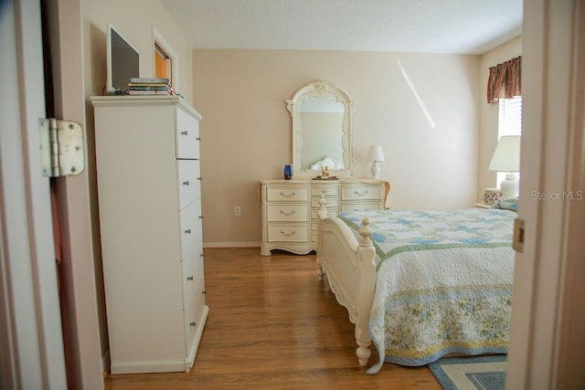 bedroom with baseboards and wood finished floors