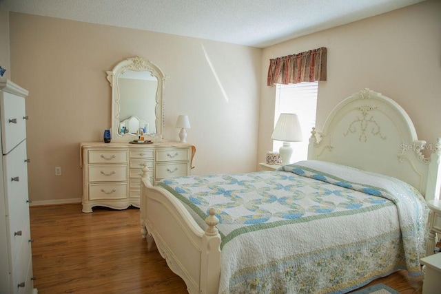 bedroom with baseboards, wood finished floors, and a textured ceiling