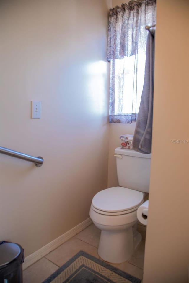 bathroom with toilet, tile patterned floors, and baseboards