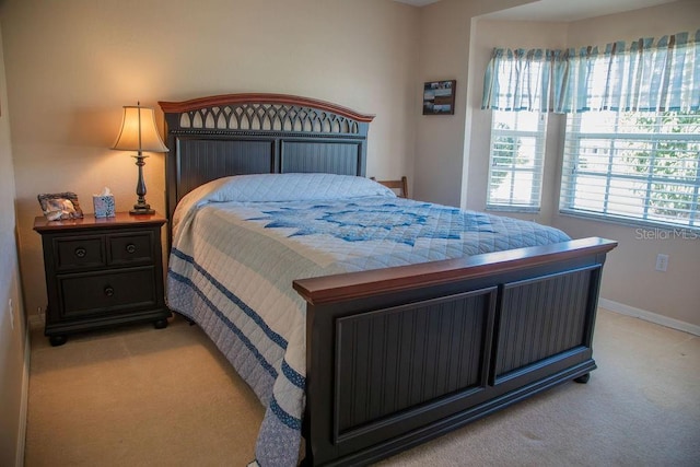 bedroom with baseboards and light carpet